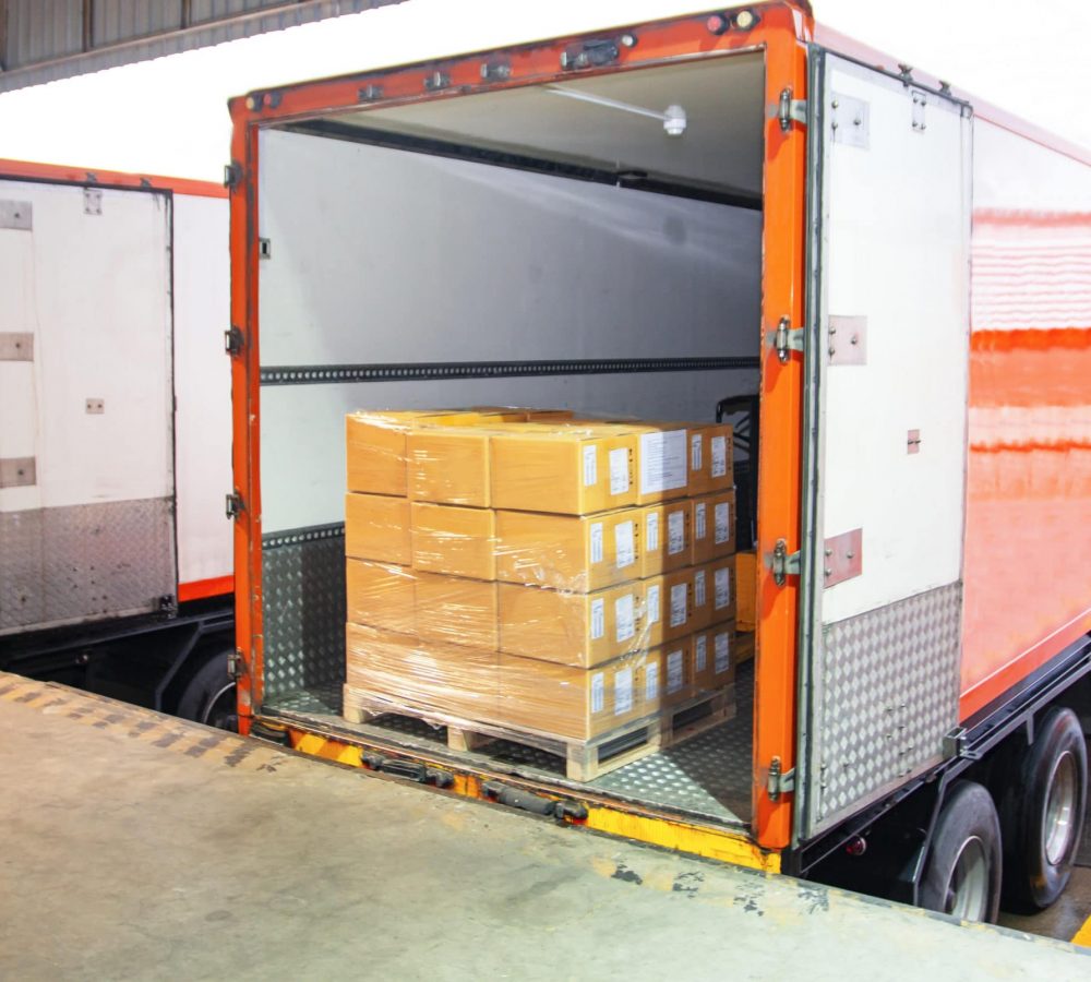 Package Boxes Load with Cargo Container. Trailer Truck Parked Loading at Dock Warehouse. Delivery Service. Shipping Warehouse Logistics. Cargo Shipment Boxes. Freight Truck Transportation.
